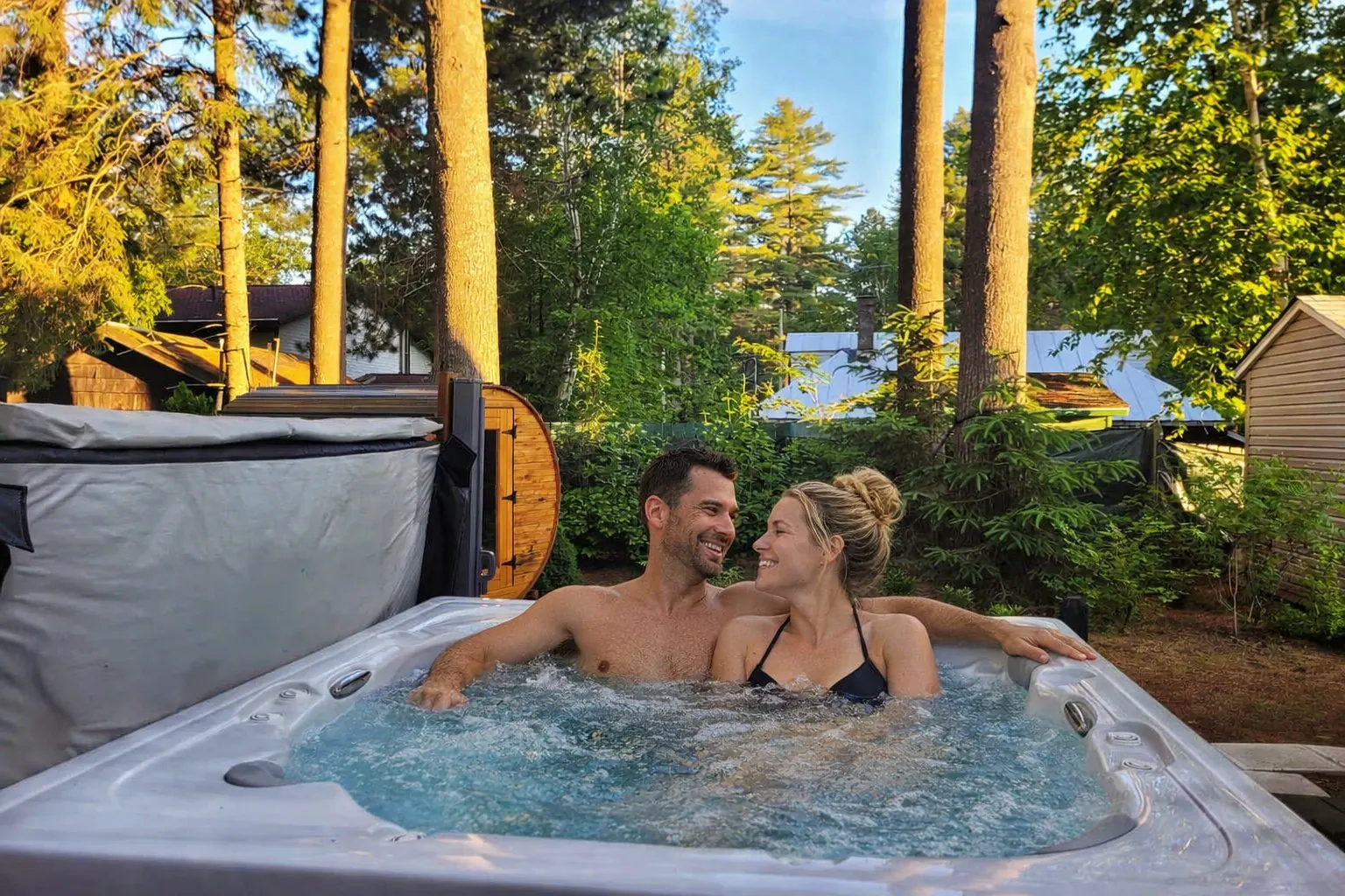 Couple profitant du spa à l’heure dorée, devant le sauna tonneau